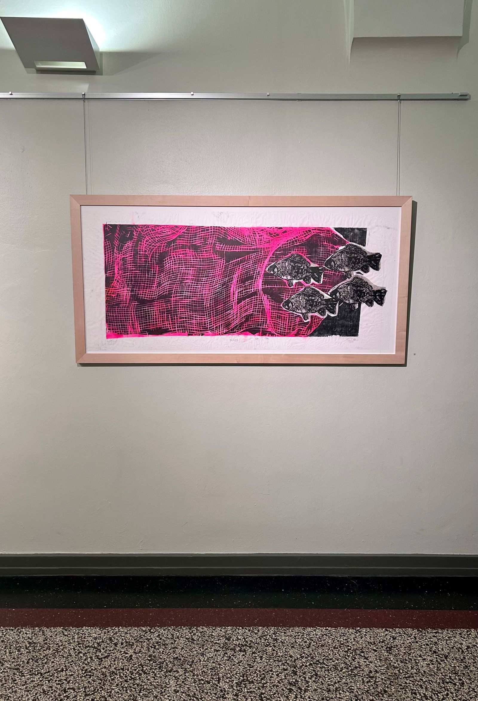 Gerahmte Arbeit in kräftigem Pink und Schwarz an einer weißen Ausstellungswand.
