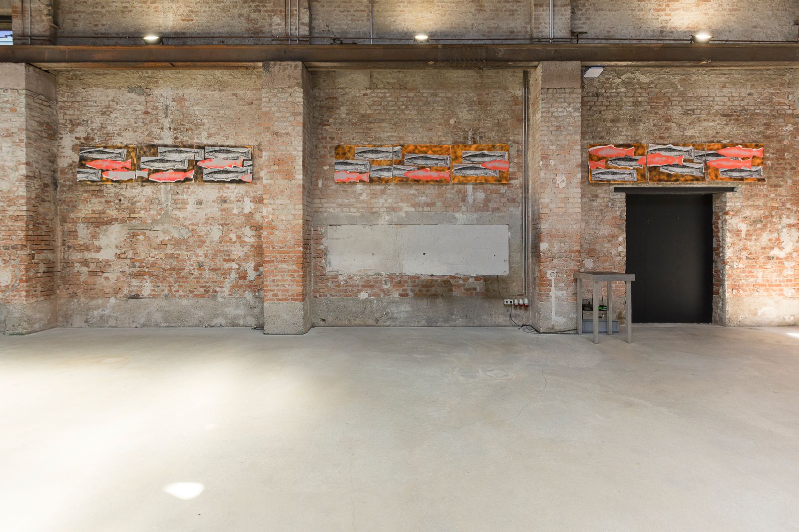 Ausstellungsansicht mit mehreren schmalen rot-weißen Arbeiten an einer Backsteinwand.
