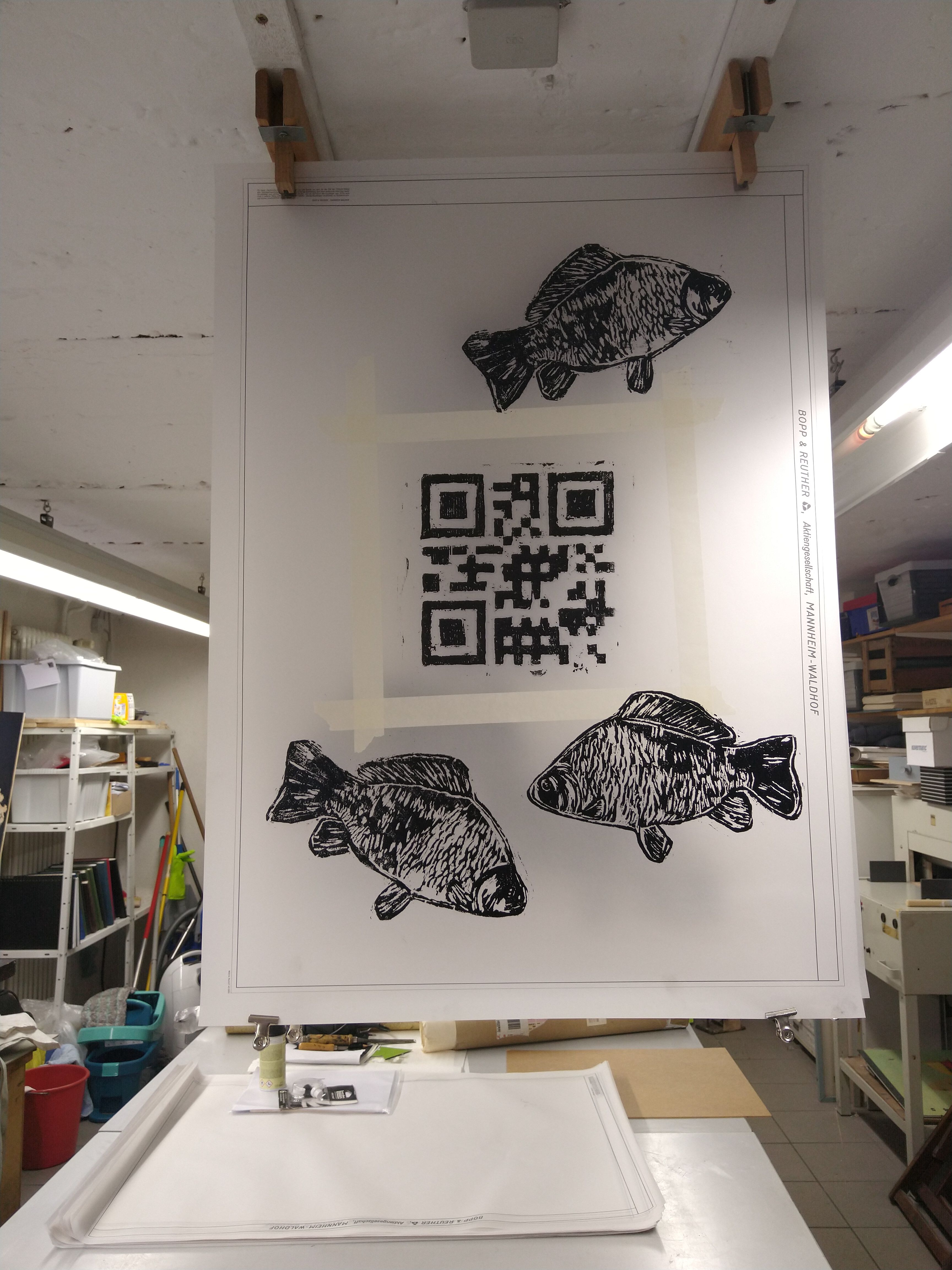 Hängende weiße Bildtafel mit schwarzen grafischen Formen und einem QR-Code im Ausstellungsraum.